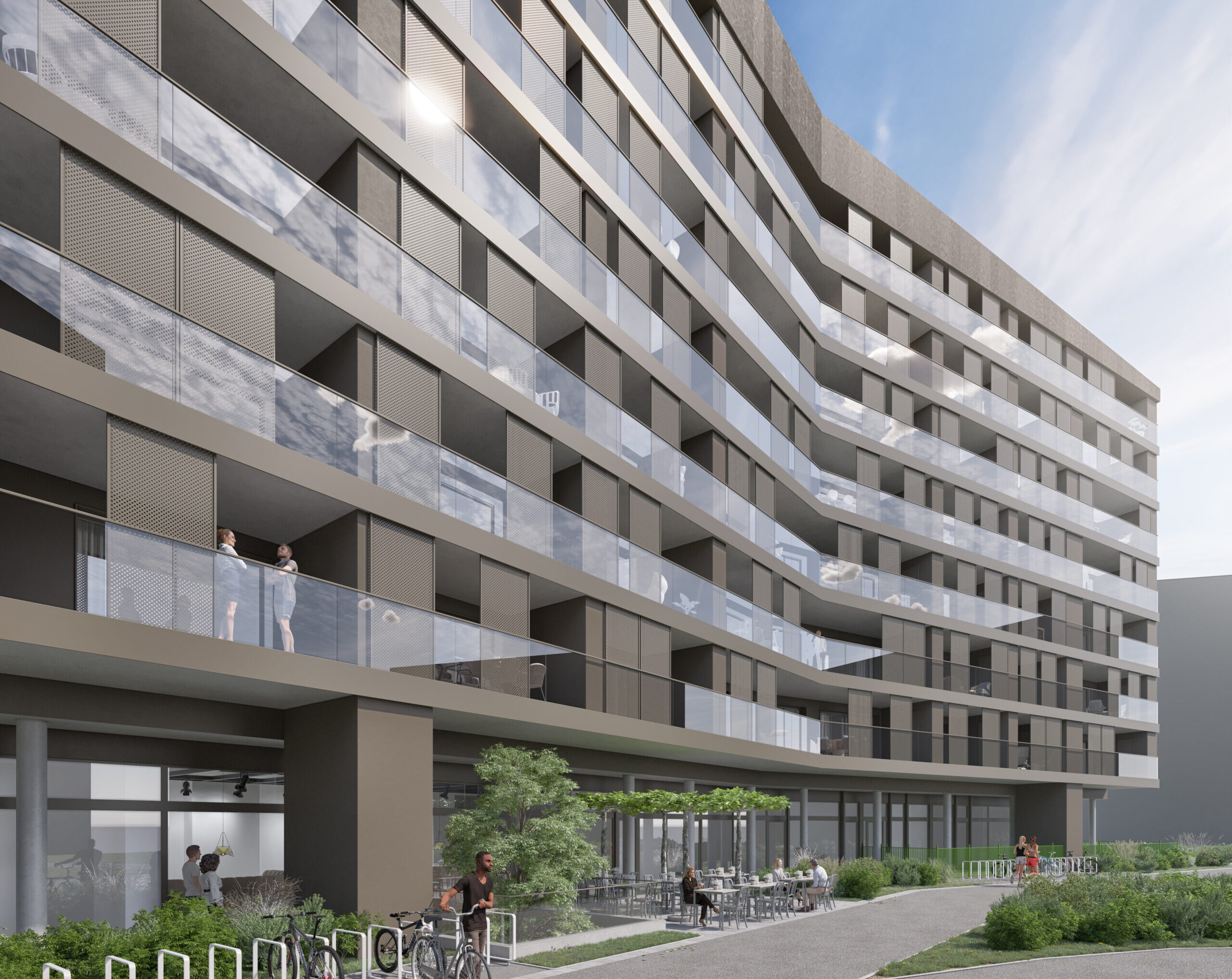 Ein modernes mehrstöckiges Wohnhaus mit Glasbalkonen und einem begrünten Innenhof. Auf einem Balkon und im Innenhof sieht man Menschen. Der Himmel ist klar und blau.